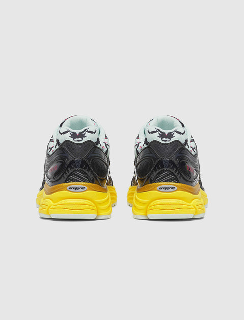Rear view of black and white sneakers with yellow soles and graphic heel design