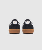 Rear view of black suede sneakers with white logo and gum soles on a light background