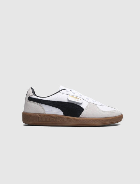 White and black suede low-top sneaker with gum sole on plain background