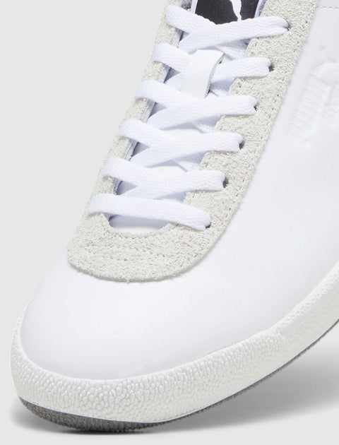 Close-up of white sneaker with suede trim, textured sole, and white laces