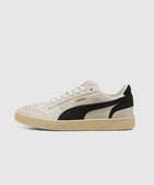 Beige and black low-top men’s sneaker with gum sole, side logo, and suede accents