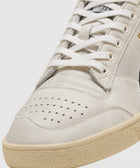 Close-up of beige and black streetwear sneaker with white laces and perforated toe box