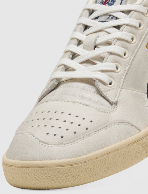 Close-up of beige and black streetwear sneaker with white laces and perforated toe box