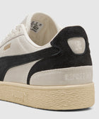 Beige and black low-top sneaker with suede accents, embossed details, and textured rubber sole