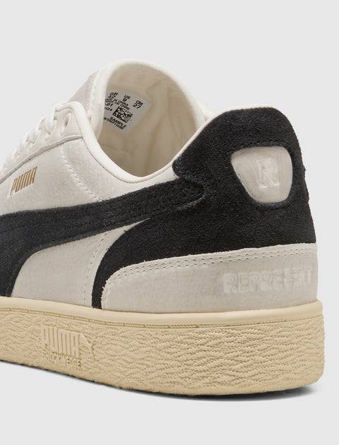 Beige and black low-top sneaker with suede accents, embossed details, and textured rubber sole