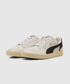 Beige and black low-top sneakers with suede details and rubber soles on white background