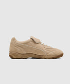 Beige suede sneaker with gum sole, lace-up and velcro strap, side profile on white background