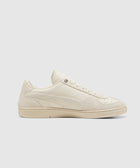 Beige low-top sneaker with suede and leather details on a plain background