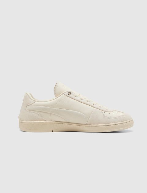 Beige low-top sneaker with suede and leather details on a plain background