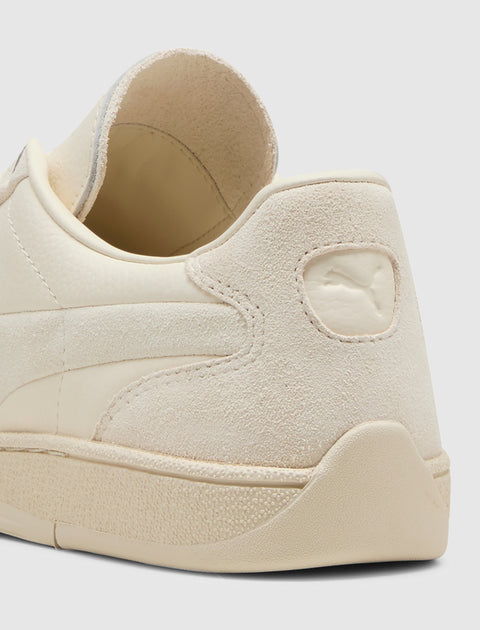 Close-up of beige suede and leather sneaker heel with embossed logo detailing