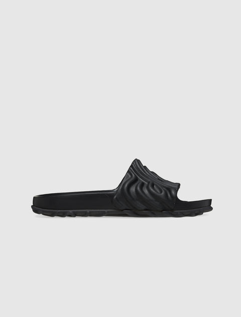 Black sculpted slide sandal with textured upper and contoured sole on white background