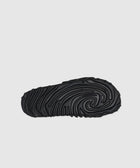 Black slide sandal outsole with textured, wavy tread pattern on white background
