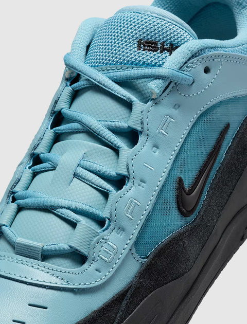 Close-up of a turquoise and black sneaker with mesh and suede textures, Nike Swoosh logo visible.