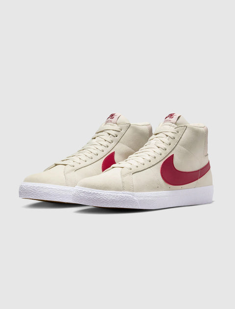 Pale ivory suede high-top sneakers with red Swoosh logo and white rubber sole on white background
