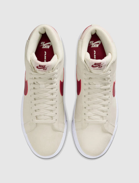 Top view of pale ivory high-top sneakers with red accents and white soles
