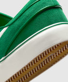 Closeup of green suede sneaker heel with white midsole and textured gum sole