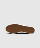 Brown gum sole of a sneaker with herringbone tread pattern on a plain background