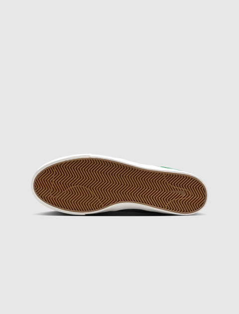 Brown gum sole of a sneaker with herringbone tread pattern on a plain background