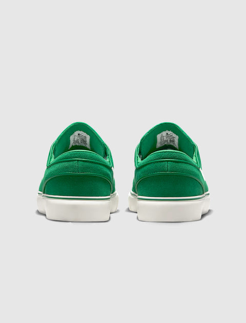 Back view of green suede low-top sneakers with white soles on gray background