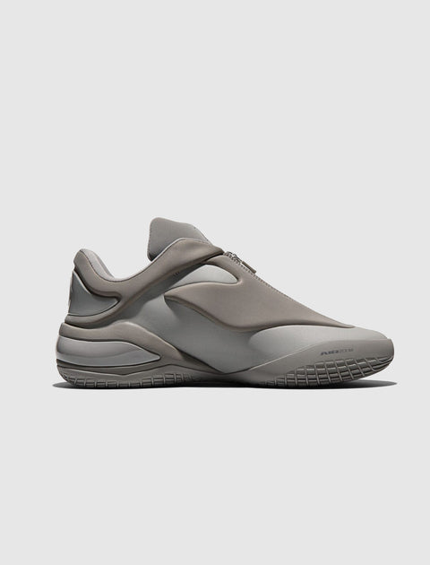 Side view of a gray low-top sneaker with sculpted sole and minimalist design
