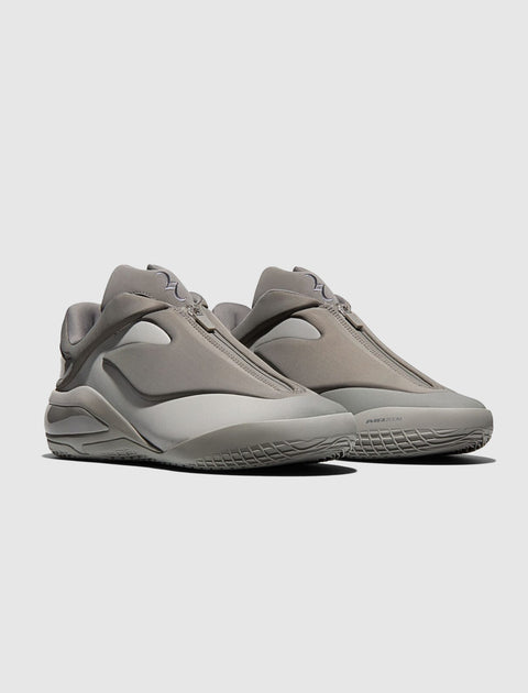 Minimalist grey slip-on sneakers with a sculpted sole, side view on light background.