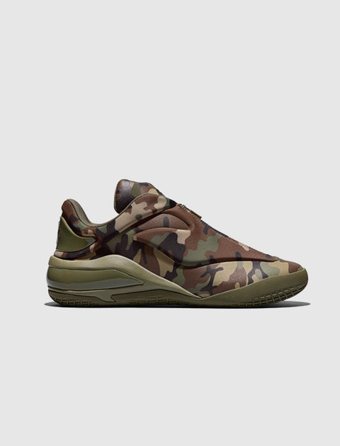 Men's low-top sneaker with green and brown camouflage pattern on a light background