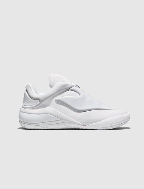 All-white modern low-top men's sneaker with sculpted details on a light gray background