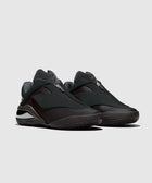 Black futuristic low-top sneakers with zip closure and chunky sole on gray background