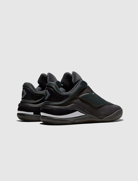 black low-top slip-on sneakers with rubber soles and white accents, rear view