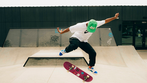 Streetwear skateboarding trick at skatepark, graphic tee, green cap, blue sneakers