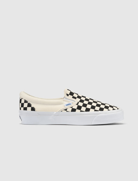 Black and white checkerboard slip-on sneaker with white sole on a plain background