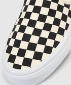 Closeup of slip-on sneaker with black and white checkerboard canvas upper and white sole