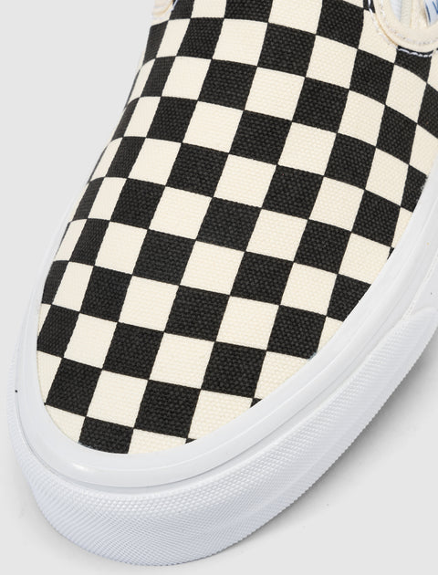 Closeup of slip-on sneaker with black and white checkerboard canvas upper and white sole