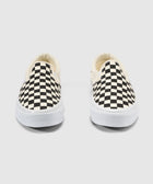 Pair of slip-on sneakers with black and white checkerboard pattern on white soles
