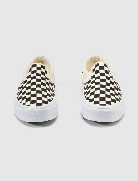 Pair of slip-on sneakers with black and white checkerboard pattern on white soles