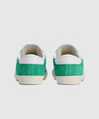 Back view of green and white suede low-top sneakers on white background