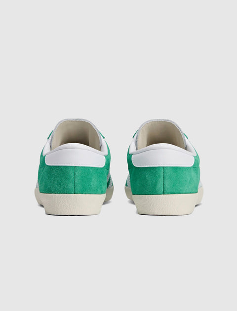 Back view of green and white suede low-top sneakers on white background