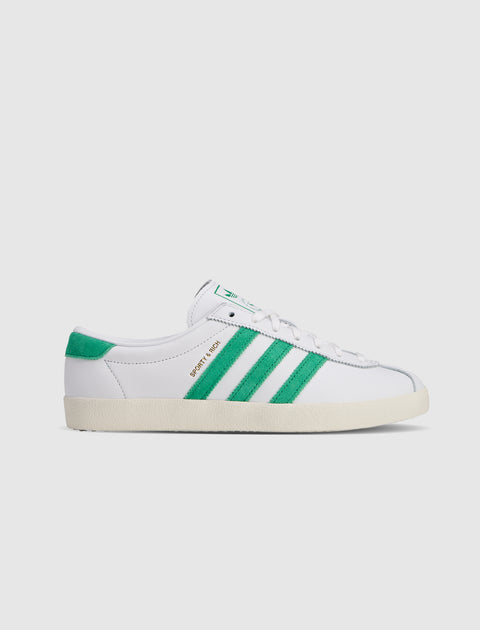 White low-top sneaker with green suede stripes and heel tab, SPORTY & RICH text on side.