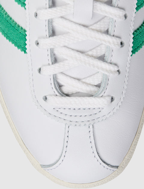 Close-up of white leather sneaker with green suede stripe and white laces