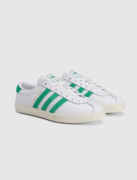White low-top sneakers with green stripes and gold side text, casual streetwear shoes.