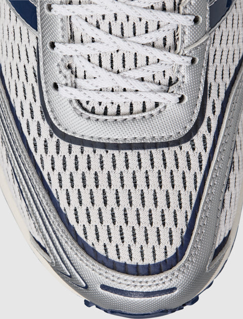 Close-up of white mesh sneaker upper with navy accents and silver trim, athletic shoe design