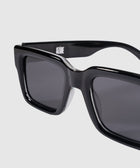 Close-up of black rectangular sunglasses with dark lenses on a light background