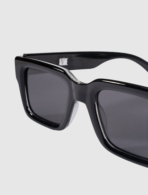 Close-up of black rectangular sunglasses with dark lenses on a light background