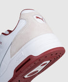 Close-up of white and beige sneaker with red outsole and suede heel accent