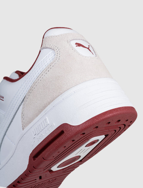 Close-up of white and beige sneaker with red outsole and suede heel accent