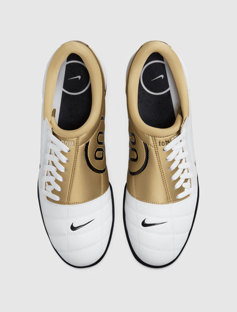 Top view of white and gold Nike sneakers with black logo, lace-up athletic shoes on white background