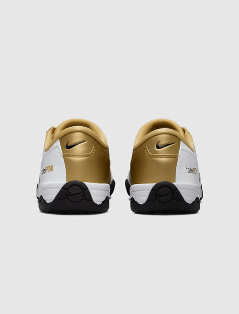 Rear view of white, black, and gold Nike sneakers with logo and total90 lettering