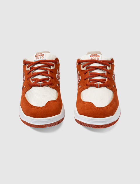 Pair of rust and white suede sneakers with mesh panels, front view, on light background