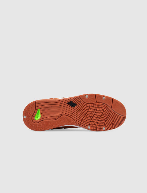 Rust-colored sneaker outsole with textured grip and New Balance logo on white background
