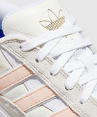 White and pink suede streetwear sneaker with gold logo and textured detailing